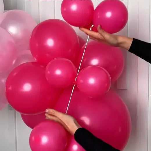 Hands gathering a bunch of hot pink balloons