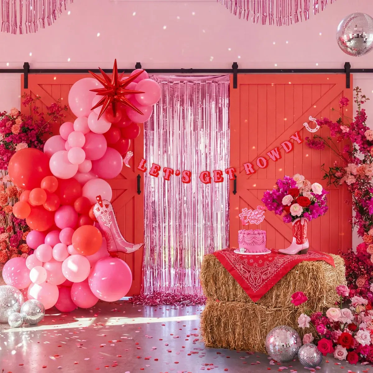A pink Rowdy Rodeo celebration with balloons, fringe curtains, disco balls and a decorated party table