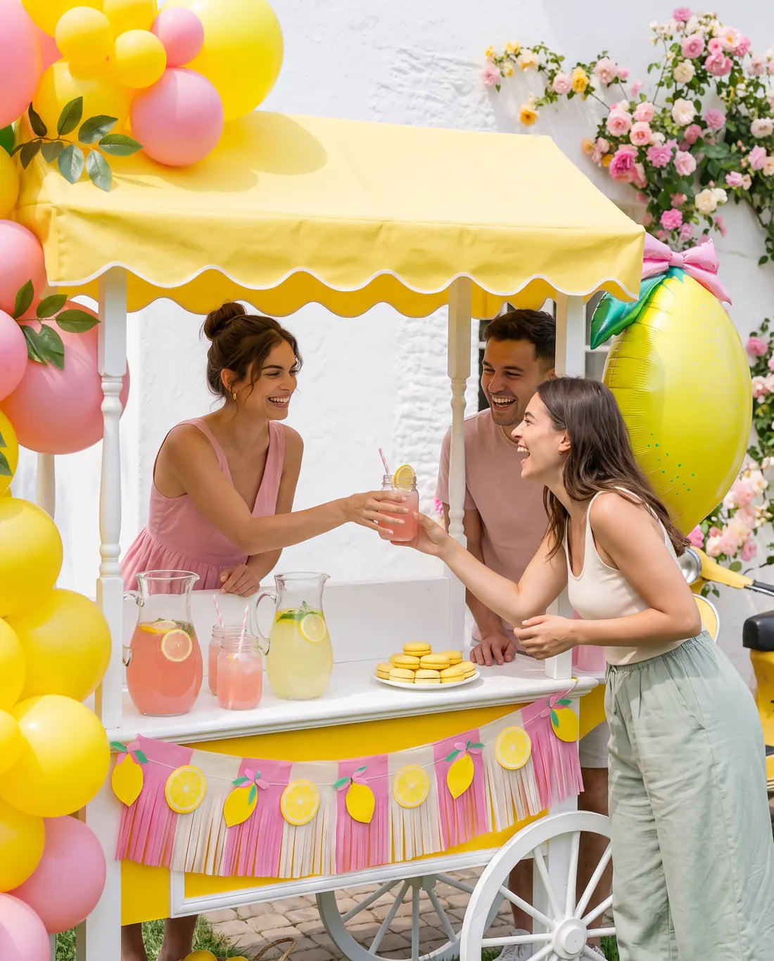 Friends at a lemonade stand decorated with yellow balloons